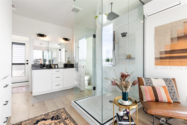 916NW 56th St Unit G, Seattle, WA 98107 - full bath with wood finished floors, a shower stall, vanity, an AC wall unit, and toilet