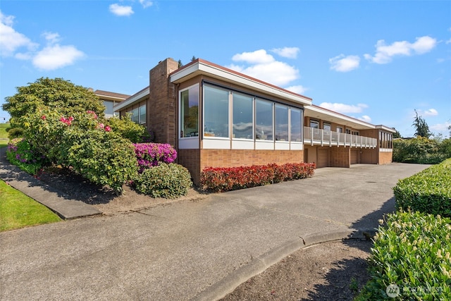 7618 19th St W, Tacoma, WA 98466 - view of front of property with brick siding, concrete driveway, a balcony, and a chimney