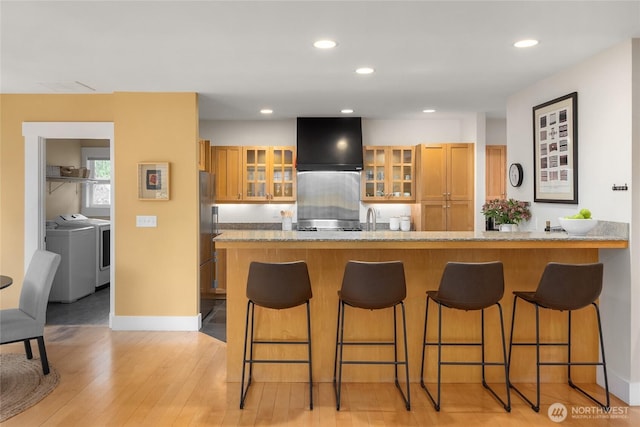 1241 Cherry Ave NE, Bainbridge Island, WA 98110 - kitchen with washing machine and clothes dryer, range hood, a kitchen breakfast bar, light wood-type flooring, and recessed lighting