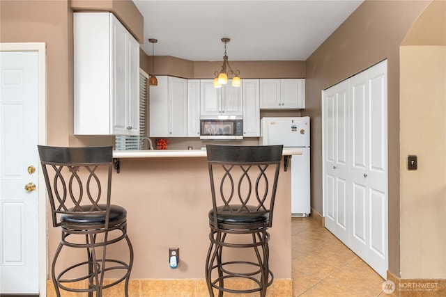 15150 140th Way SE Unit V104, Renton, WA 98058 - kitchen featuring stainless steel microwave, freestanding refrigerator, white cabinets, a kitchen breakfast bar, and a peninsula