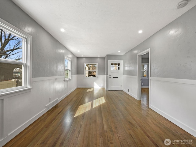 unfurnished living room with wood finished floors, a wainscoted wall, and recessed lighting