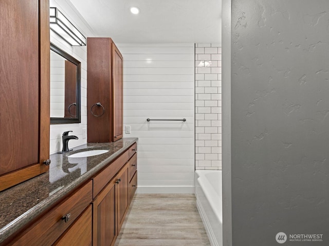 full bathroom with wood finished floors, vanity, a bathtub, baseboards, and a shower