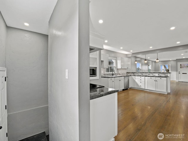 kitchen with appliances with stainless steel finishes, a peninsula, white cabinetry, recessed lighting, and dark wood finished floors