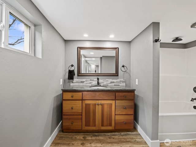 full bathroom with decorative backsplash, wood finished floors, baseboards, and recessed lighting