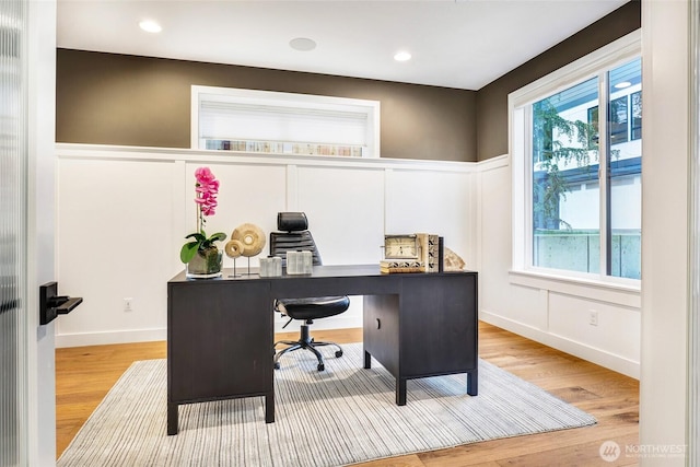 office area with wood finished floors, a decorative wall, and wainscoting