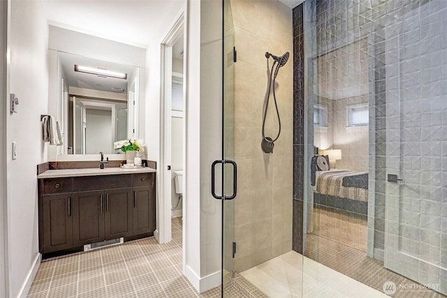 bathroom with a stall shower, toilet, vanity, tile patterned flooring, and baseboards
