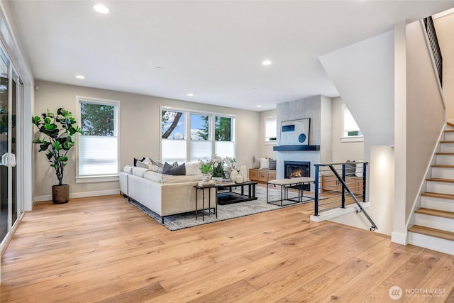 living room with light wood-type flooring, recessed lighting, a fireplace, stairs, and baseboards