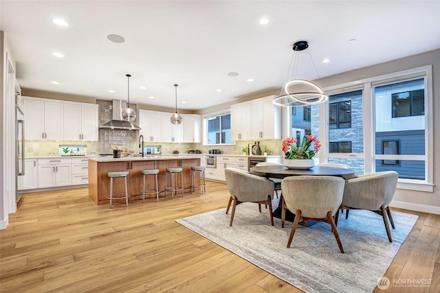 dining room featuring light wood finished floors, recessed lighting, and wine cooler