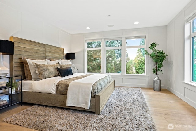 bedroom with wood finished floors, a decorative wall, and recessed lighting