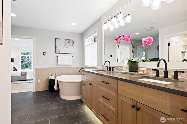 full bathroom with a freestanding tub, double vanity, ensuite bath, wainscoting, and recessed lighting