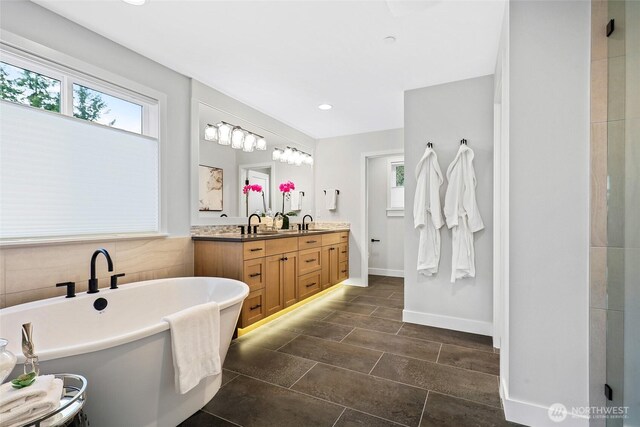 full bath with a freestanding bath, double vanity, baseboards, and recessed lighting
