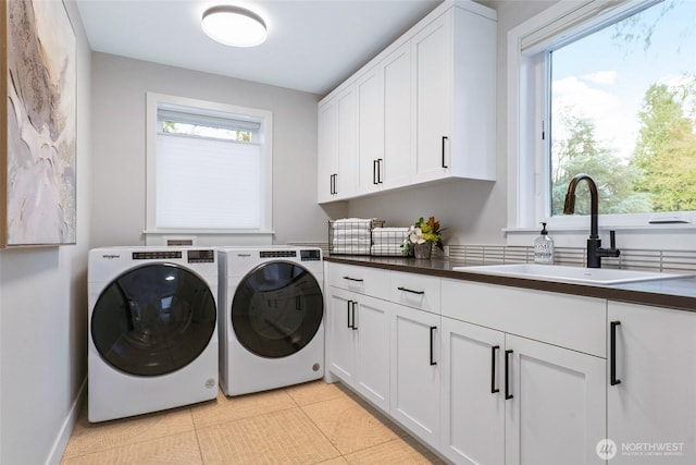 washroom featuring cabinet space, washing machine and clothes dryer, and light tile patterned floors