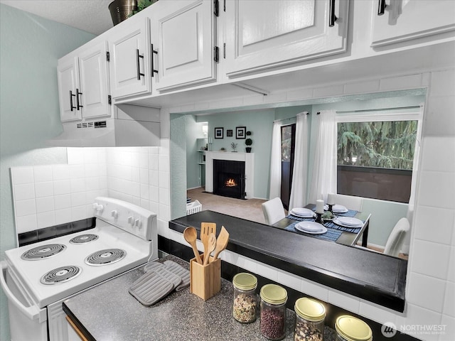 3024 NE 143rd St Unit 304, Seattle, WA 98125 - kitchen with white range with electric cooktop, under cabinet range hood, white cabinetry, and a lit fireplace
