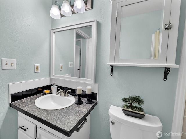 3024 NE 143rd St Unit 304, Seattle, WA 98125 - bathroom featuring toilet, vanity, tasteful backsplash, and a textured wall