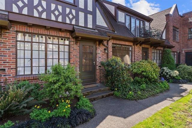 doorway to property featuring a balcony and brick siding