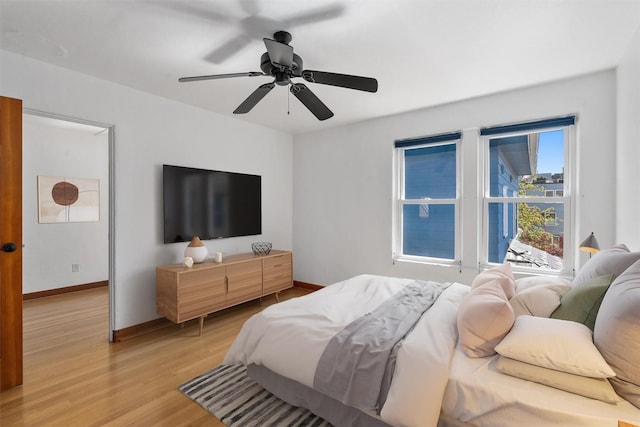 bedroom with light wood finished floors, baseboards, and ceiling fan