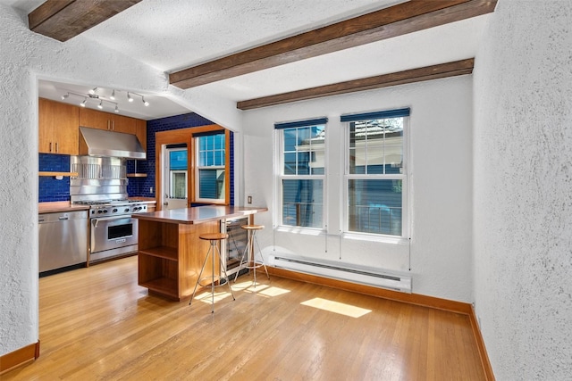 kitchen with baseboard heating, stainless steel appliances, a textured wall, under cabinet range hood, and open shelves