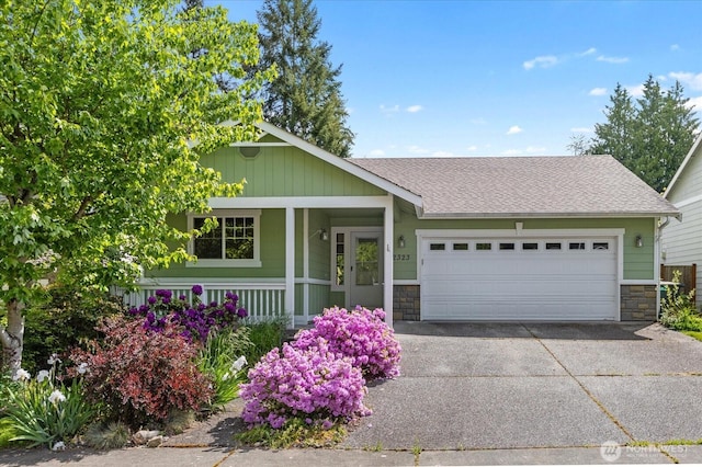 2323 Baird Ave, Snohomish, WA 98290 - view of front of house featuring stone siding, concrete driveway, a garage, covered porch, and roof with shingles