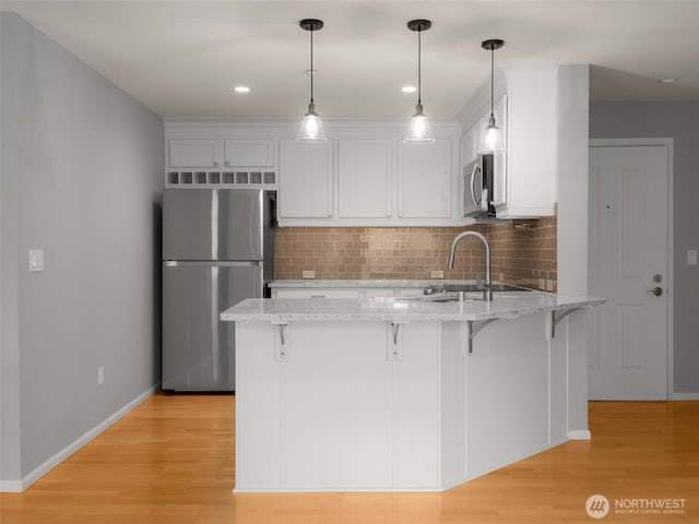 23925 NE 115th Ln Unit 302, Redmond, WA 98053 - kitchen featuring appliances with stainless steel finishes, a peninsula, white cabinets, a kitchen breakfast bar, and decorative backsplash