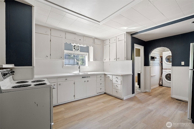 3510 N Puget Sound Ave, Tacoma, WA 98407 - kitchen with white range with electric cooktop, stacked washer / dryer, a sink, wainscoting, and light wood-type flooring