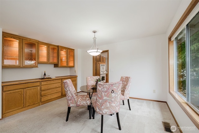 dining area featuring light colored carpet and baseboards