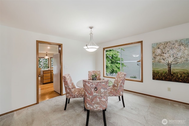 dining area featuring light carpet and baseboards