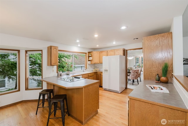 kitchen featuring white fridge with ice dispenser, black electric cooktop, a peninsula, light wood-type flooring, and a kitchen bar