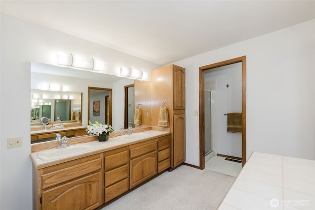 bathroom featuring a shower stall, double vanity, and baseboards
