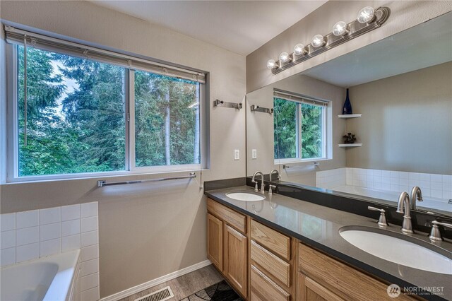 20282 NW Cedar Ln, Poulsbo, WA 98370 - bathroom with a bath, double vanity, wood finished floors, and baseboards