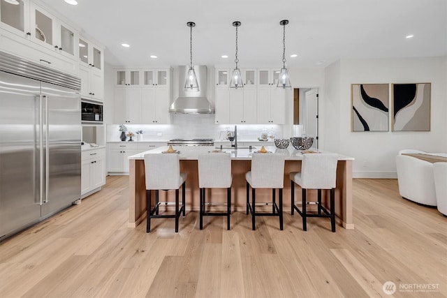 43268 SE 145th Pl, North Bend, WA 98045 - kitchen with built in appliances, wall chimney range hood, backsplash, light countertops, and light wood-type flooring