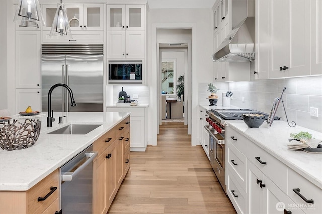 43268 SE 145th Pl, North Bend, WA 98045 - kitchen with built in appliances, a sink, wall chimney exhaust hood, light wood-style flooring, and tasteful backsplash