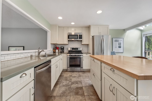 kitchen with appliances with stainless steel finishes, a sink, backsplash, recessed lighting, and a kitchen island