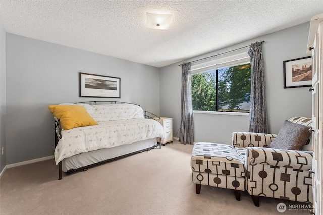 bedroom featuring light carpet, a textured ceiling, and baseboards