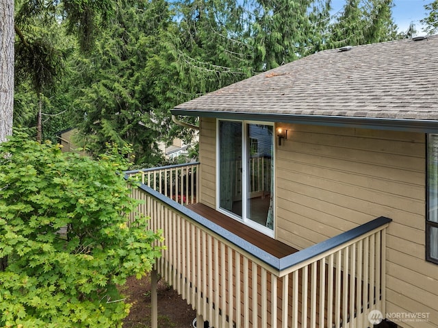 view of property exterior featuring a shingled roof and a wooden deck