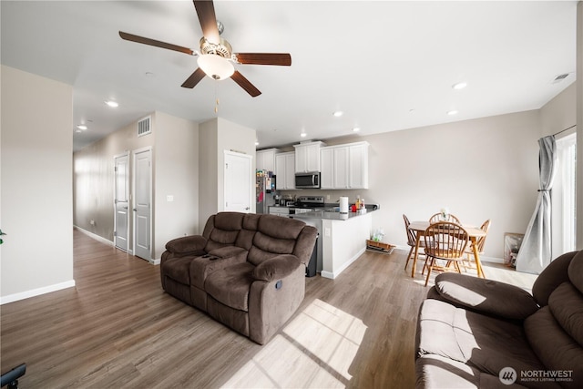 living room with a ceiling fan, light wood-type flooring, baseboards, and recessed lighting