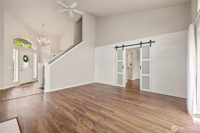 7521 Sterling Pl, Arlington, WA 98223 - unfurnished living room featuring a barn door, high vaulted ceiling, a ceiling fan, wood finished floors, and a chandelier