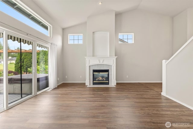 7521 Sterling Pl, Arlington, WA 98223 - unfurnished living room with vaulted ceiling, a tiled fireplace, wood finished floors, and baseboards