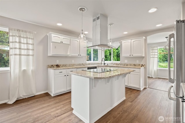 7521 Sterling Pl, Arlington, WA 98223 - kitchen with island range hood, freestanding refrigerator, white cabinetry, arched walkways, and black electric cooktop