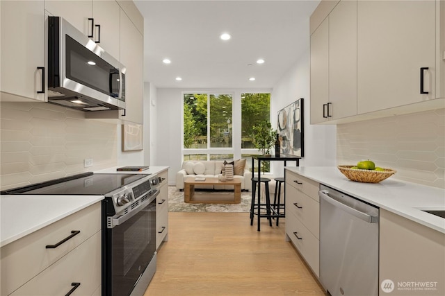 1523 N 39th St, Seattle, WA 98103 - kitchen featuring stainless steel appliances, recessed lighting, light wood-type flooring, backsplash, and light countertops