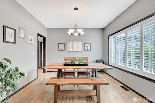 dining space with healthy amount of natural light, a chandelier, and light wood-type flooring