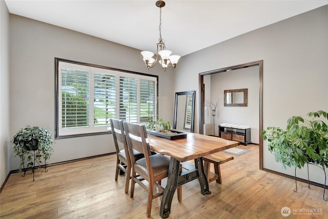 dining area featuring a chandelier, light wood-style flooring, and baseboards
