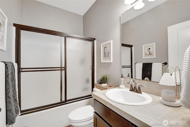 bathroom with vanity, shower / bath combination with glass door, and toilet