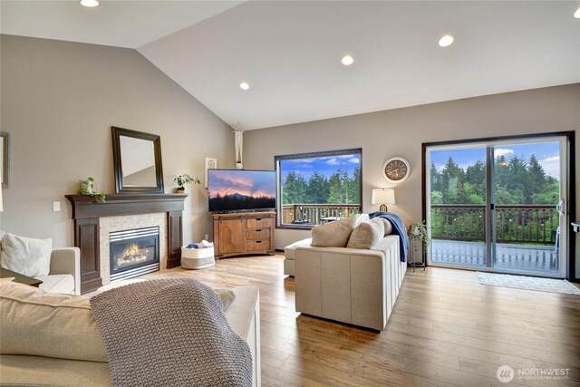 living area with lofted ceiling, a tiled fireplace, wood finished floors, and recessed lighting