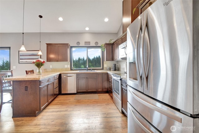 kitchen featuring appliances with stainless steel finishes, a sink, a peninsula, healthy amount of natural light, and recessed lighting