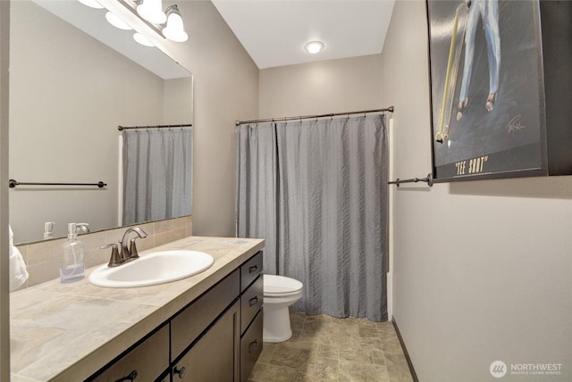 bathroom featuring stone finish floors, toilet, vanity, a shower with shower curtain, and backsplash