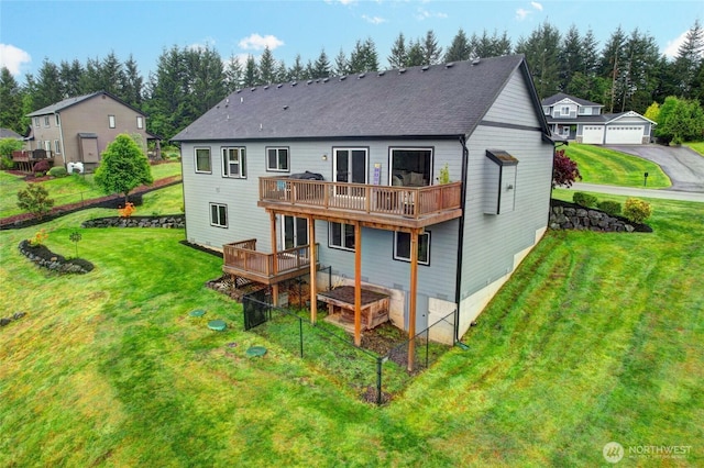 back of house featuring a deck, a yard, and roof with shingles