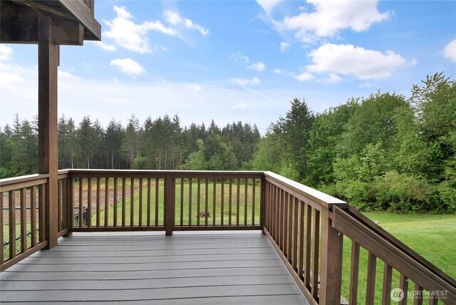 deck with a lawn and a view of trees