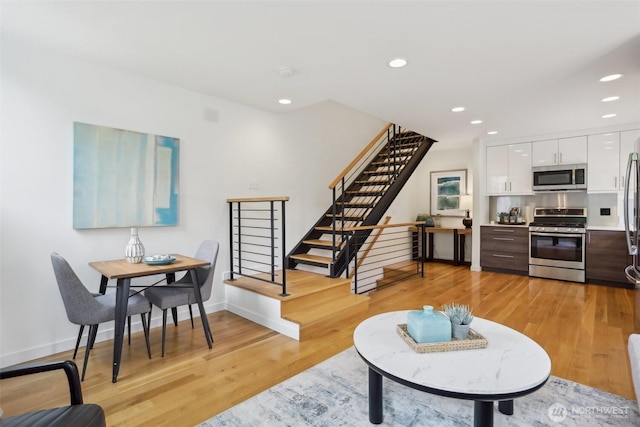 living area with stairs, recessed lighting, light wood-type flooring, and baseboards