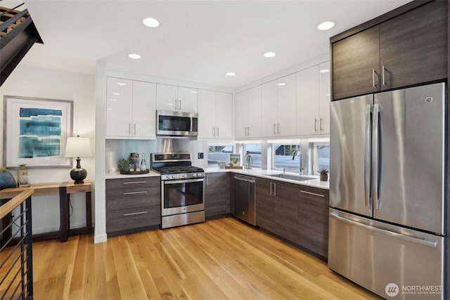 kitchen featuring stainless steel appliances, a sink, modern cabinets, light countertops, and recessed lighting