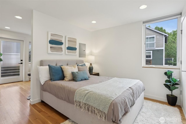 bedroom featuring wood finished floors, baseboards, recessed lighting, and electric panel